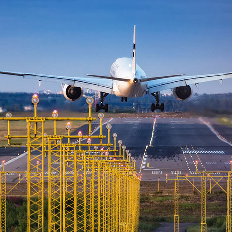 An airplane takes off from a runway near an electrical substation
