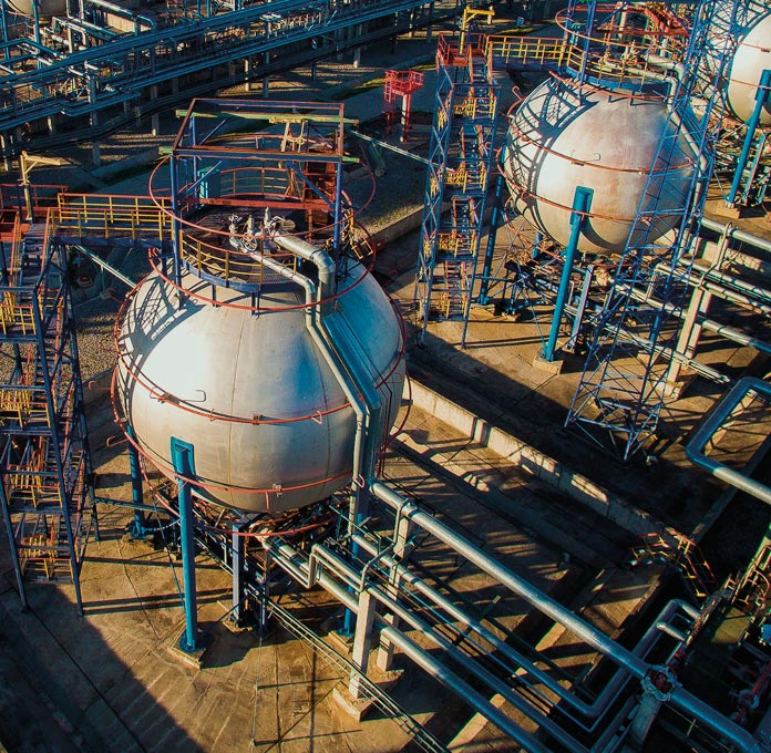 Aerial view of large spherical storage tanks and surrounding pipelines at an industrial facility.