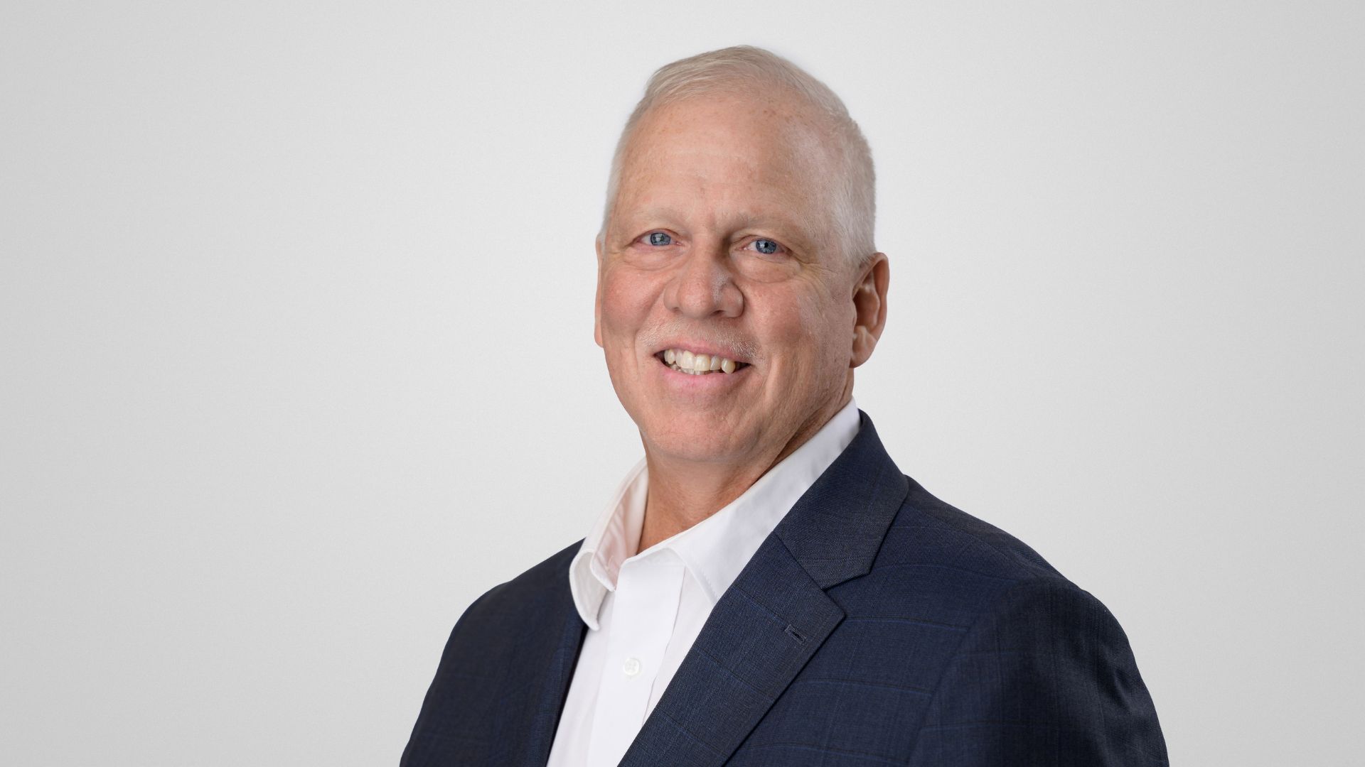 Professional headshot of Senior Advisor Don Huller wearing a navy blazer and white collared shirt, facing slightly to the side against a plain light gray background.