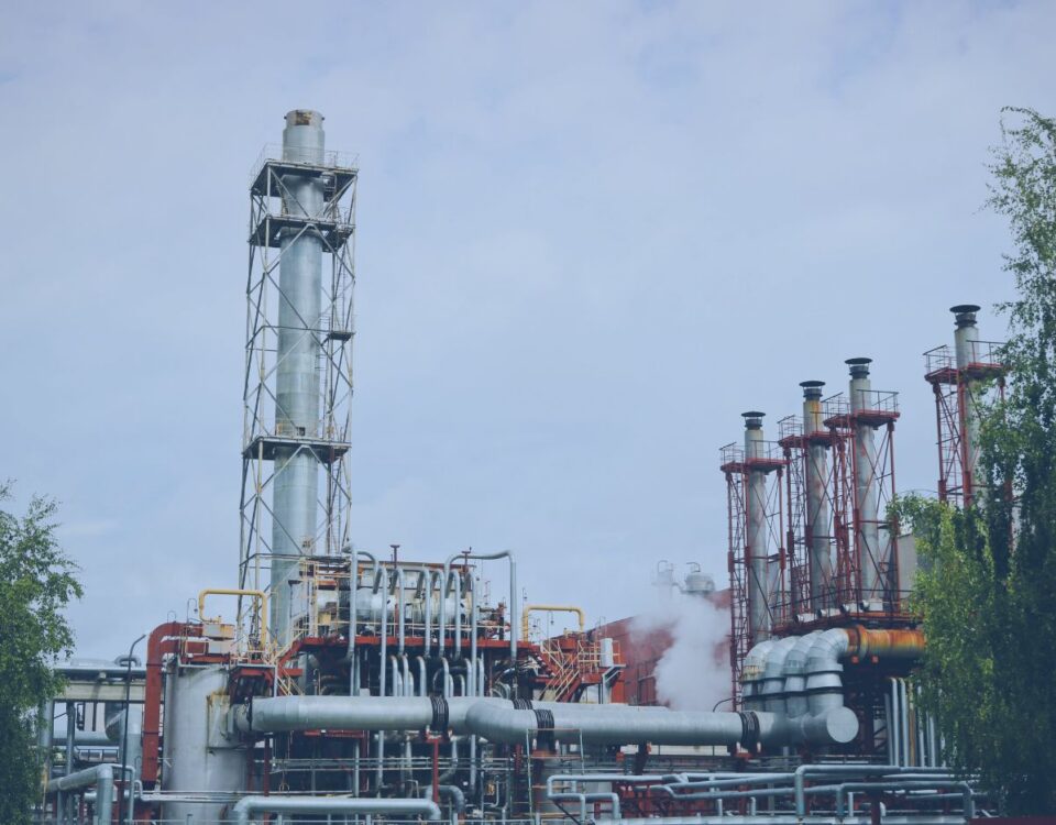 Cogeneration facility with industrial process equipment, heat recovery systems, piping networks, and exhaust stacks used for combined heat and power (CHP) generation. Steam is visible near the process units, highlighting energy production and operational infrastructure within a power and energy plant.